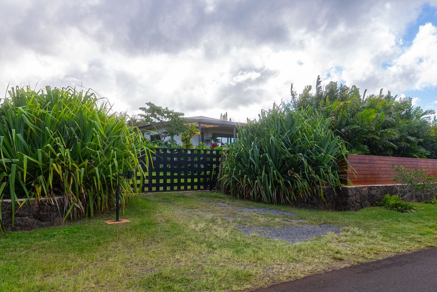 Enter through a charming garden gate bordered by lush greenery and island plantings.