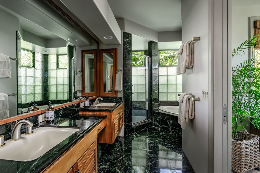 Elegant bathroom featuring marble finishes, dual sinks, and a jetted tub