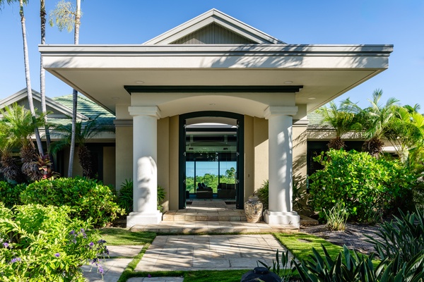 Grand entrance with tall columns and lush landscaping, offering a warm and welcoming arrival to the home.