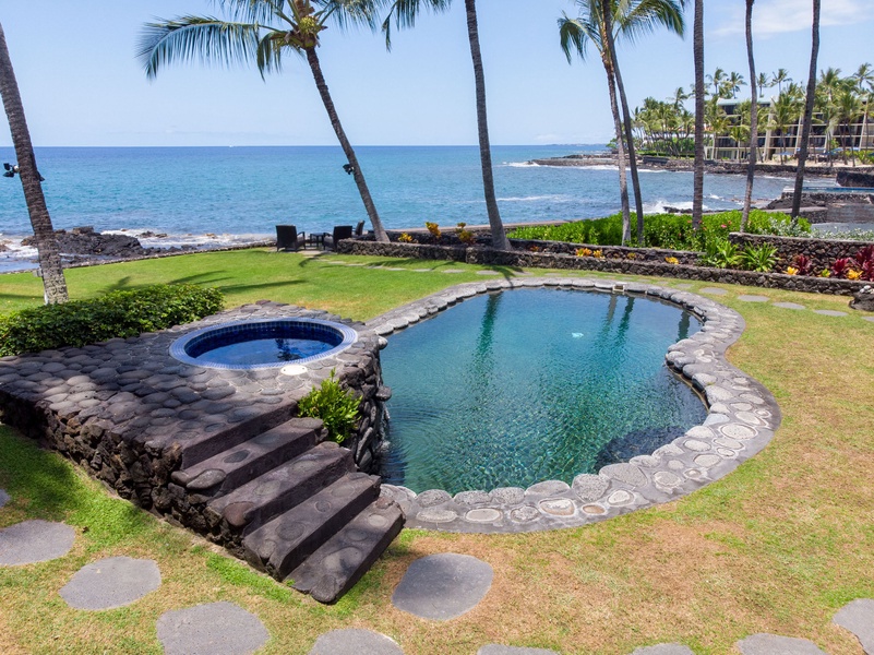 Oceanfront paradise with private pool and hot tub surrounded by swaying palms and turquoise waters stretching to the horizon.