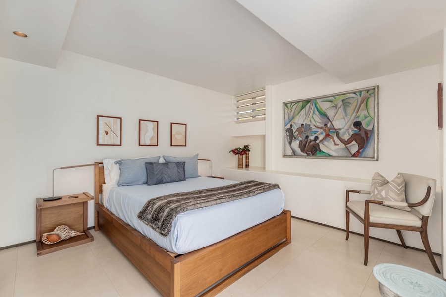 Guest suite with a cozy king bed on a wooden-framed bed that anchors the space, complemented by curated art pieces that breathe life into the pristine walls.