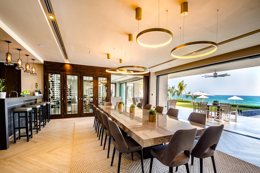 Dine in style in the elegant dining area, featuring a long marble table and direct access to the outdoor patio with panoramic ocean vistas.