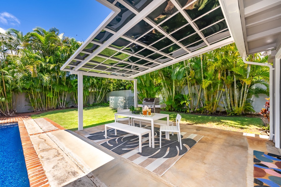 Your private outdoor dining oasis awaits—picture yourself enjoying meals al fresco under a stylish pergola, surrounded by lush tropical palms, green lawns, and your own sparkling pool.