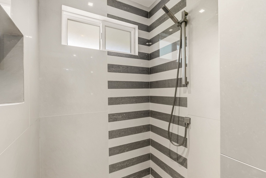 Step into your private shower featuring bold horizontal stripes and a sleek handheld fixture. Fresh, modern tiles create a spa-like retreat where you can unwind after your day's adventures.