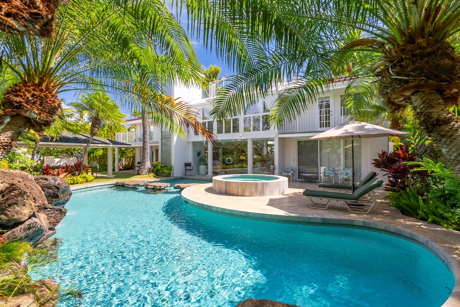 Beautiful pool area surrounded by palm trees and tropical plants, perfect for a relaxing outdoor experience.