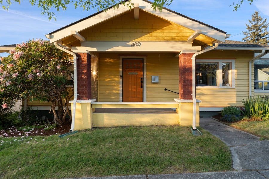 Step onto the inviting front porch framed by classic columns and mature landscaping.