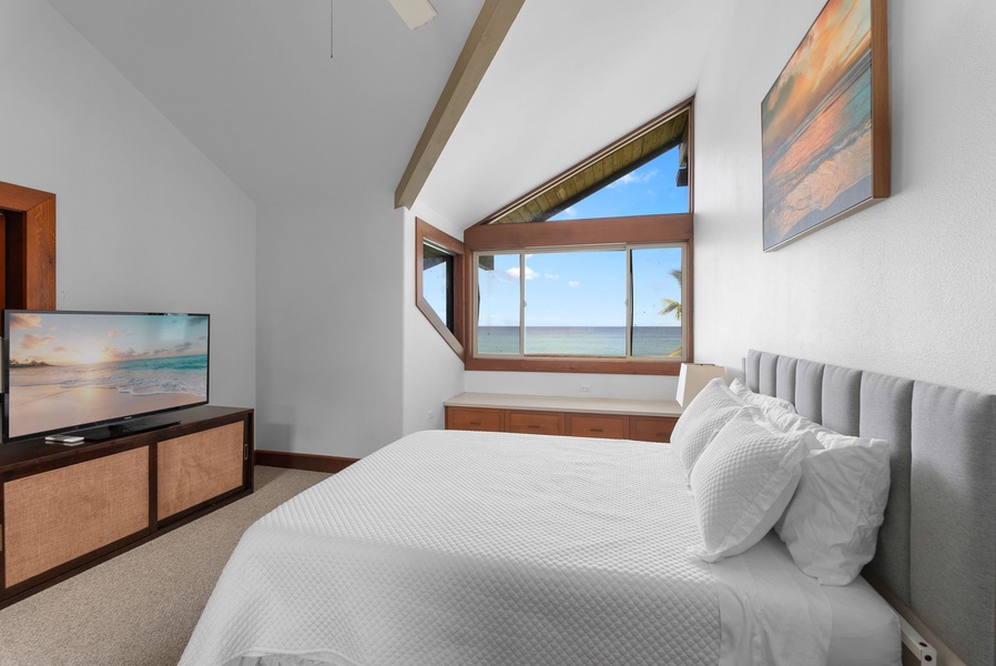 Guest bedroom with large windows showcasing ocean views.