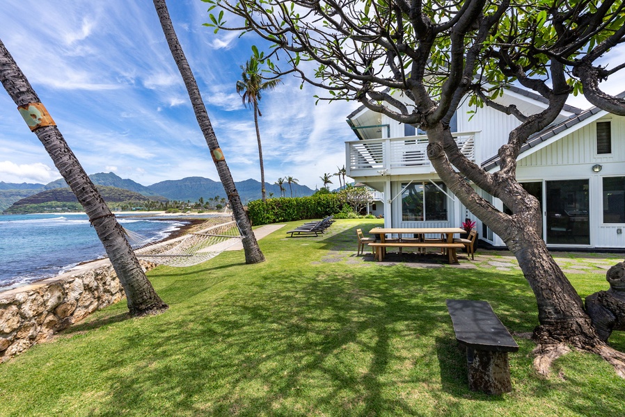 Oceanfront property with direct beach access, featuring lush landscaped grounds and mountain backdrop.