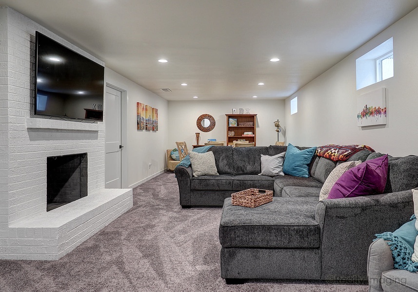 The basement is the ultimate comfort zone with soft carpeting, a massive plush sectional sofa, and an ambient wood-burning fireplace