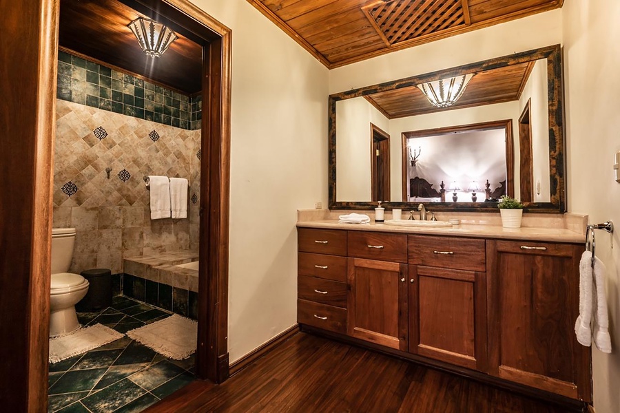 Rustic ensuite bathroom with rich wooden cabinetry and a spacious tiled shower.