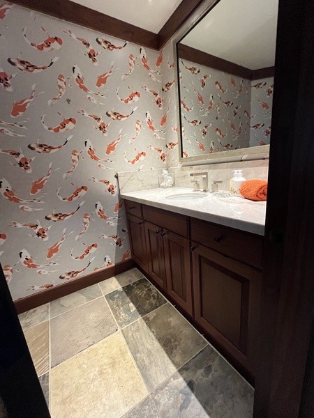 Distinctive wallpaper and stone floors in this home's powder room