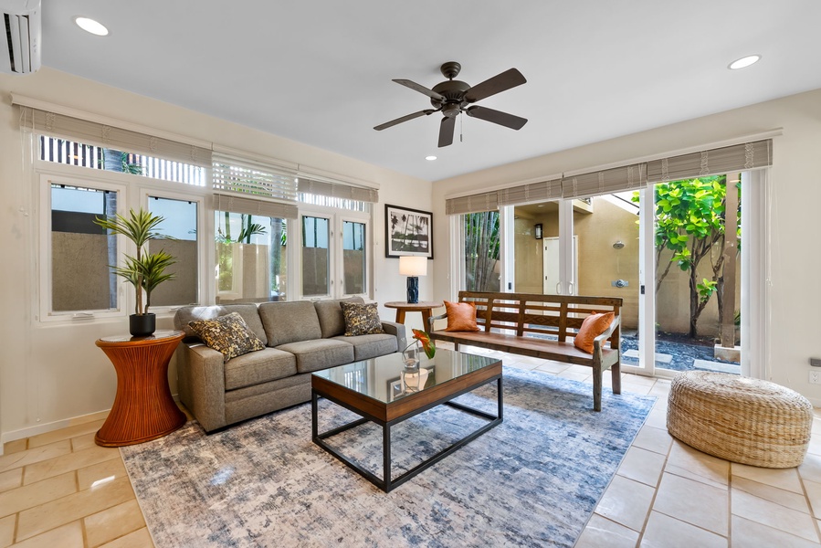 Sink into the plush sofa and let the ceiling fan's gentle breeze cool you as natural light floods through panoramic windows.
