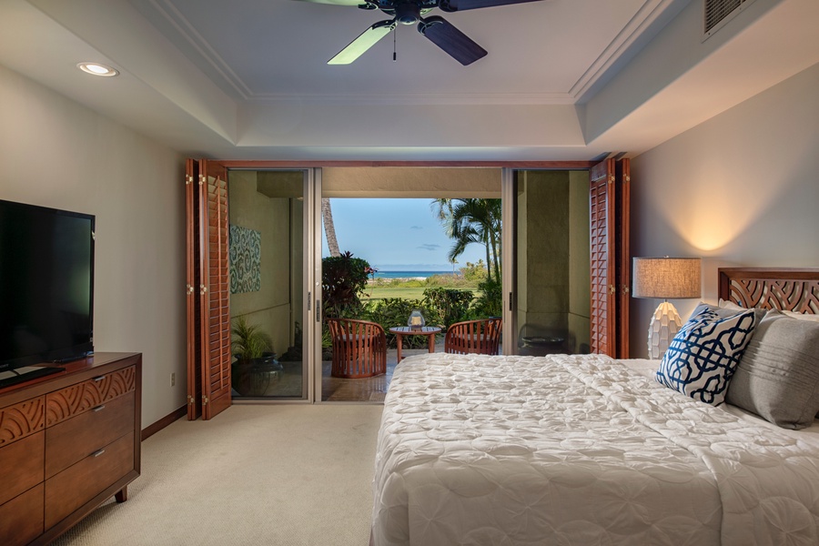 Primary bedroom w/king bed, flat screen TV, sliding doors to private ocean view lanai & ensuite bath.