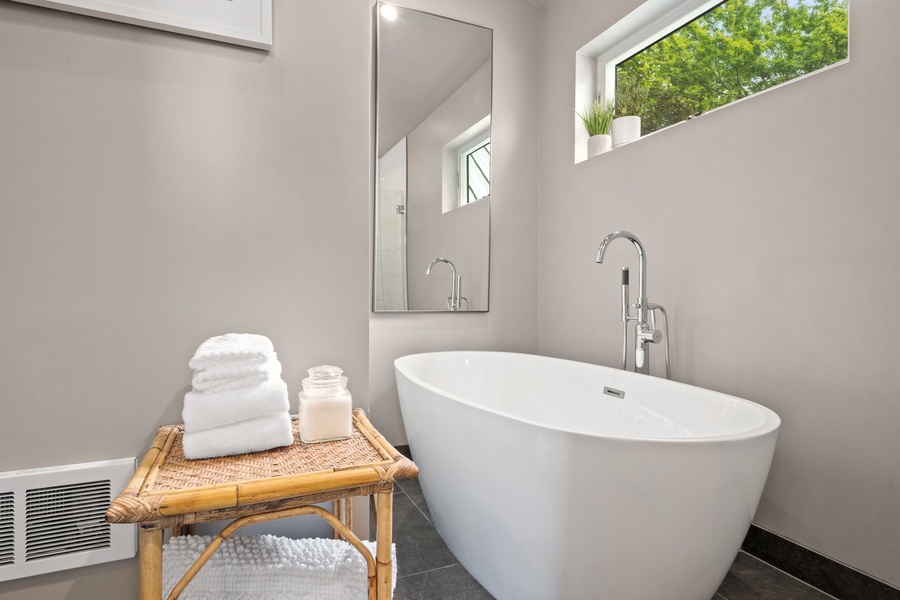 Soaking tub sits beneath a sunny window—perfect for slow mornings.