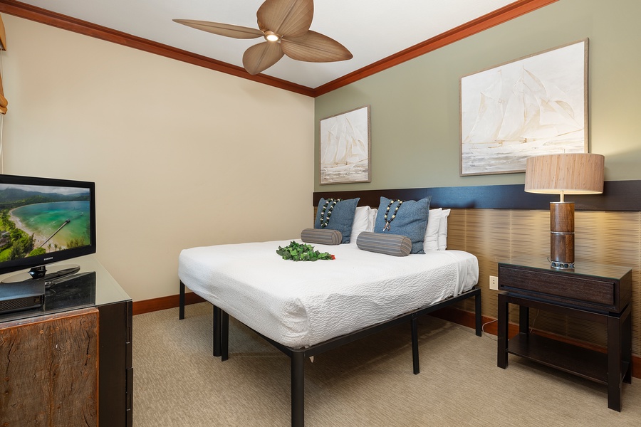 Your serene bedroom retreat features a comfortable bed, modern TV, and tropical ceiling fan for restful nights.