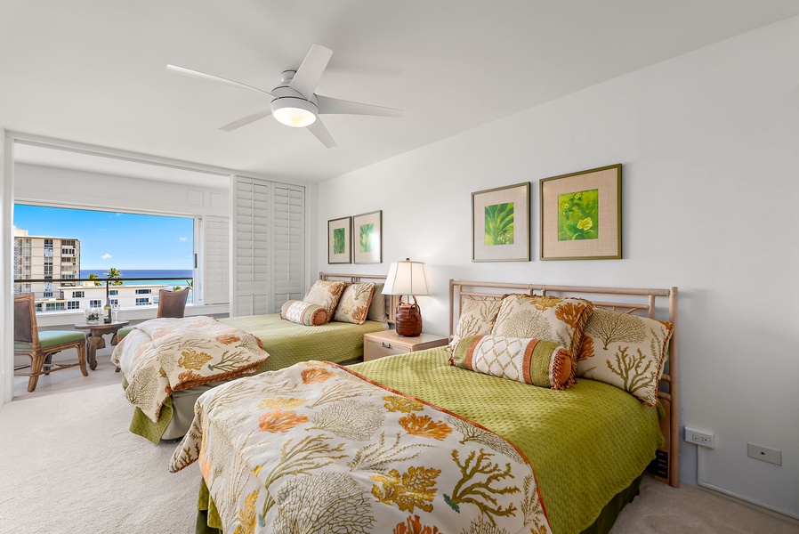 Guest bedroom offers two beds with colorful island linens and ocean glimpses—perfect for friends or kids.