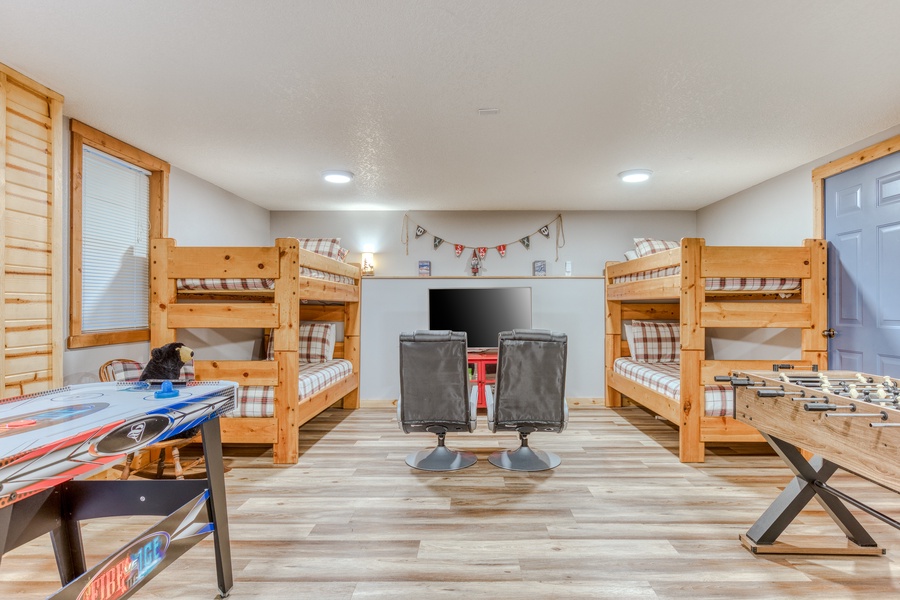 Kids' bedroom with two twin-over-twin bunk beds, TV, lots of game options, X-box and gaming chairs.