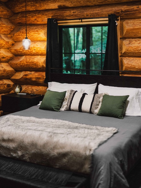 Rest comfortably in the cozy cabin bedroom surrounded by warm wood interiors.