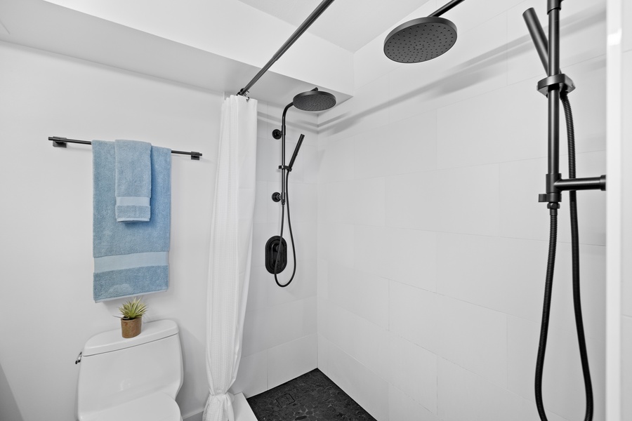 Step into this modern shower featuring a sleek black rain shower head and a minimalist design for a refreshing experience.