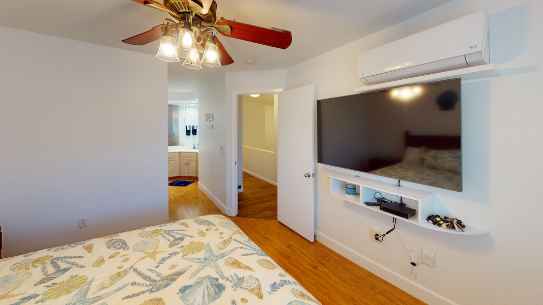 The primary guest bedroom with large tv, ceiling fan and delicate seashell touches.