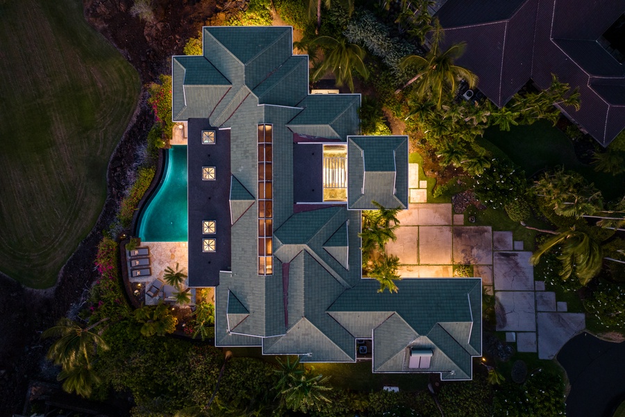 Aerial view of Champion Ridge 24, a luxurious home at dusk, with warm lighting and a private pool.