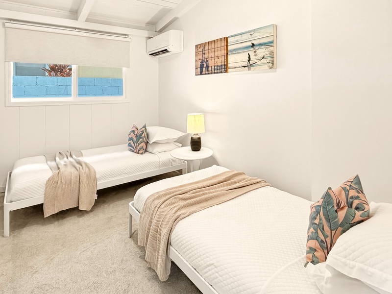 Drift off peacefully in your coastal-themed twin bedroom, where natural light streams through windows and tropical touches create your serene retreat.
