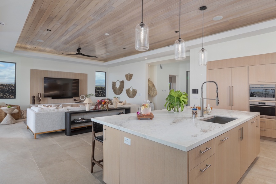 This modern kitchen is a chef's dream, featuring sleek marble countertops, state-of-the-art appliances, and ample storage within light wood cabinetry.