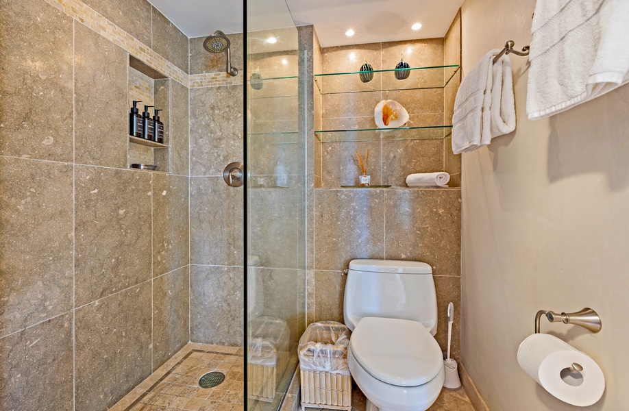 The bathroom features a spacious walk-in shower with elegant tile and built-in shelving for a clean and modern look.