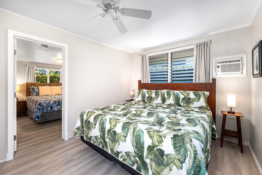 Guest bedroom with king bed, ceiling fan, and lush garden views.