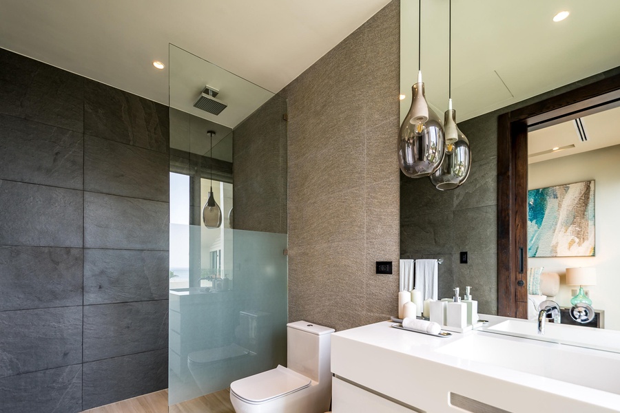 Refresh in the sleek and modern ensuite bathroom, featuring glass accents and elegant lighting.