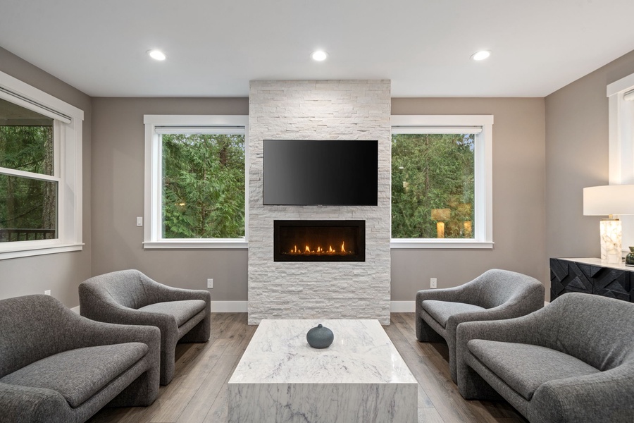 Plush seating around the elegant stone fireplace, where warm flames and natural light create your perfect retreat.