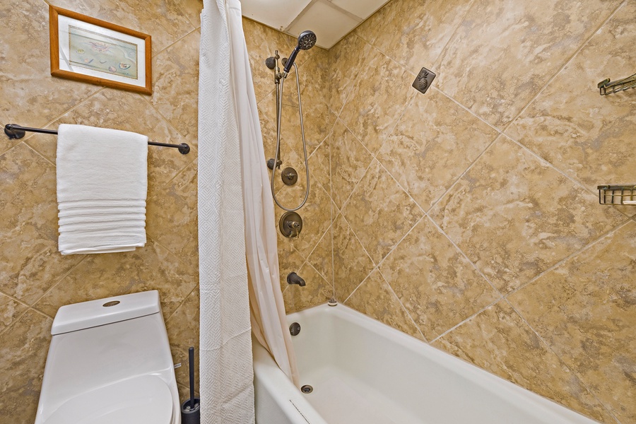 This bathroom boasts a beautifully tiled shower and bath combo, offering a relaxing space to unwind after a day of exploring