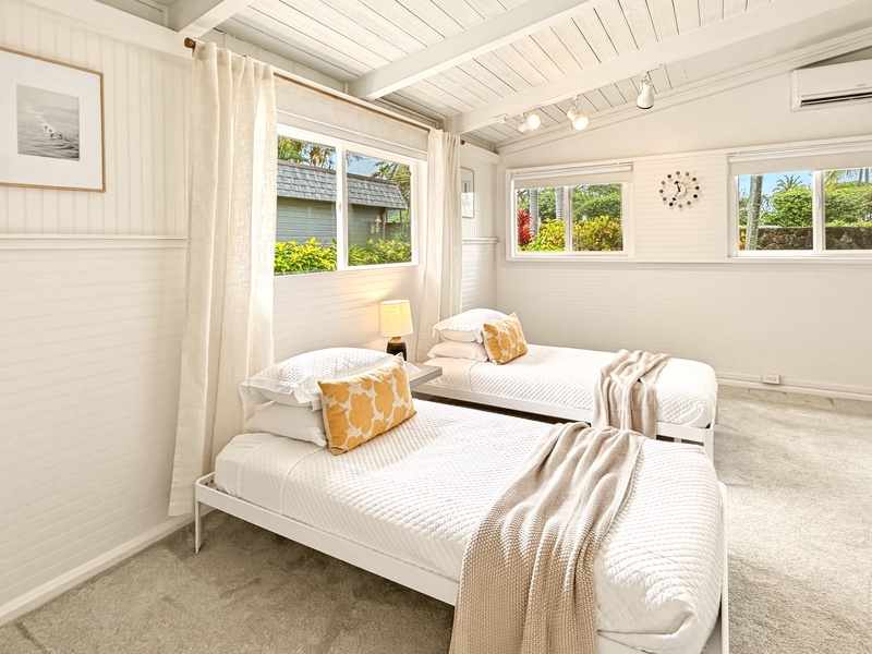 Your peaceful twin bedroom features crisp linens and garden views, perfect for restful nights with natural light streaming through multiple windows.