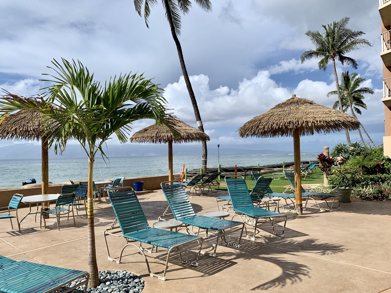 Lounge under the shade of a thatched umbrella and enjoy the ocean breeze by the water.