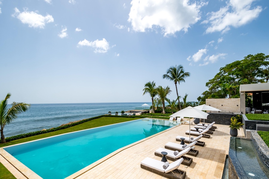 Panoramic view of the ocean from the luxurious infinity pool, surrounded by manicured lawns and tropical landscaping.