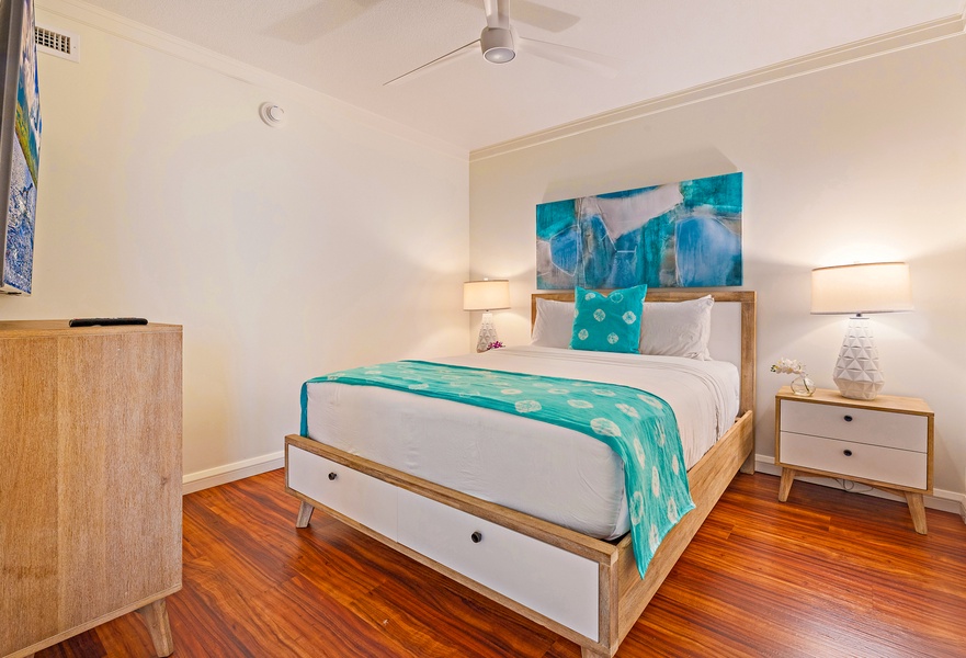 The bedroom features warm wooden floors, a stylish bed with turquoise accents, and a modern ceiling fan