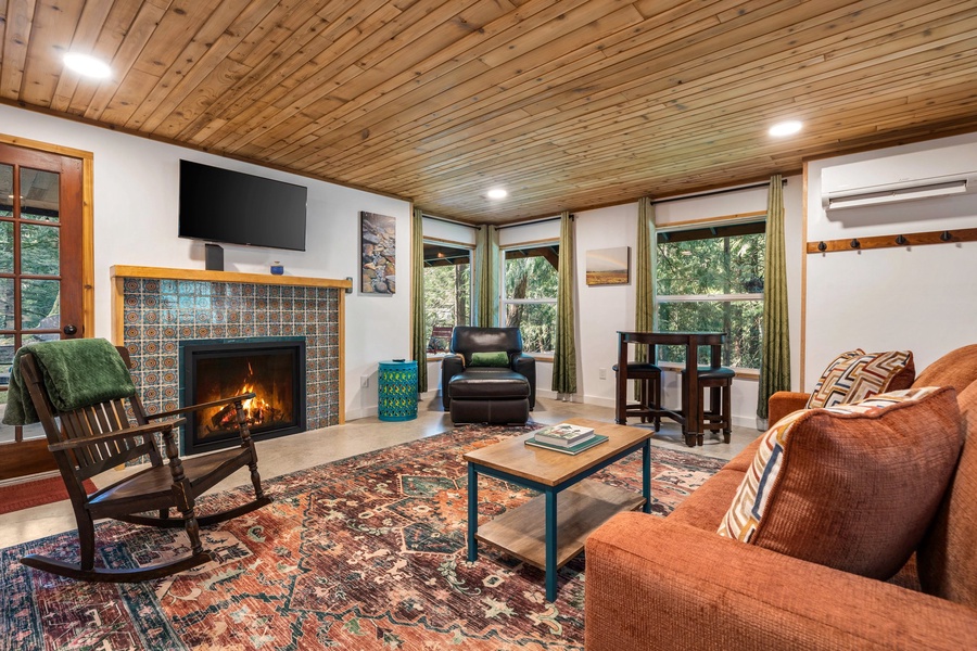 The cozy living room offers warm wood finishes, an electric fireplace, and smart TV—ideal for movie nights or quiet afternoons.