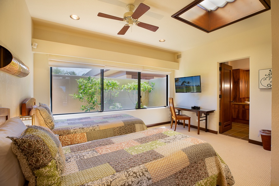 Tranquil guest bedroom with two twin beds, vaulted ceilings, and a serene tropical view.
