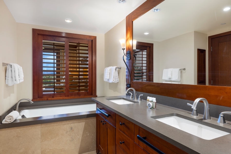 The primary guest bathroom has a walk-in shower and a luxurious bath, creating a spa-like experience in your island escape.