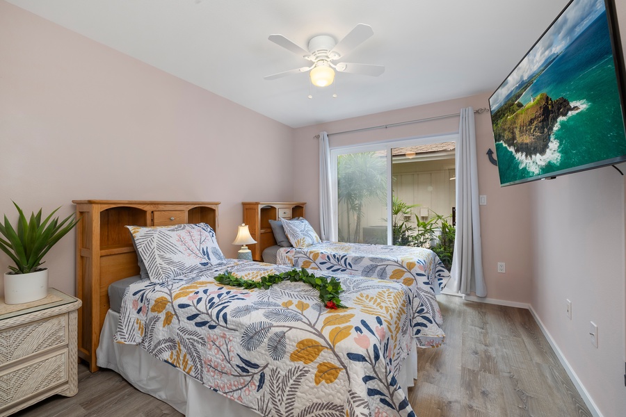 Comfortable second bedroom with two twin beds and a ceiling fan—perfect for kids or traveling friends.
