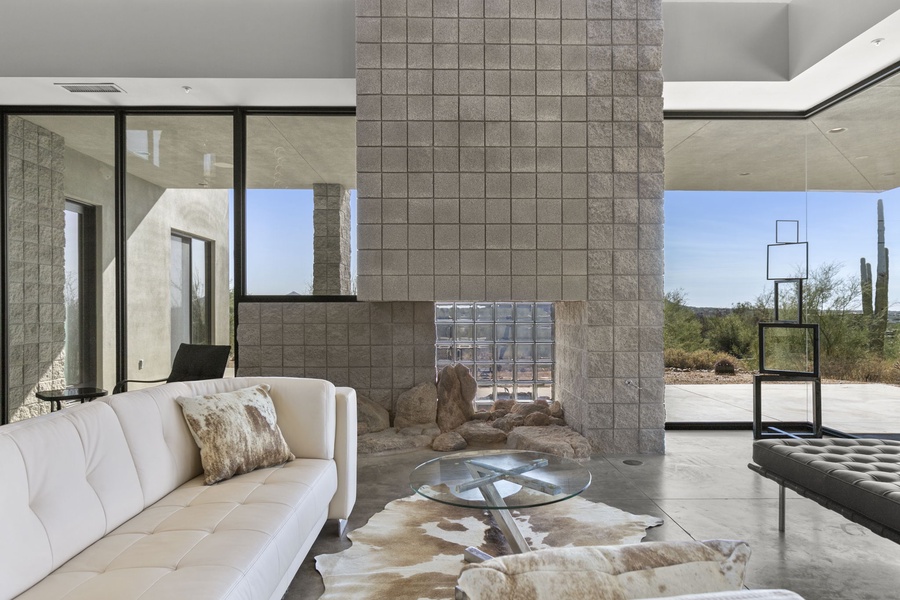Contemporary elegance unfolds in this airy living space, featuring a unique central fireplace and expansive views through the innovative glass corners.