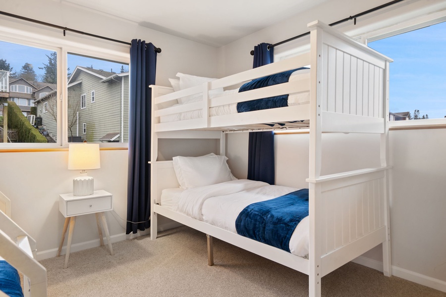 Your kids will love this bright bunk bed room with comfy white linens and cheerful blue accents, perfect for peaceful nights after busy vacation days.