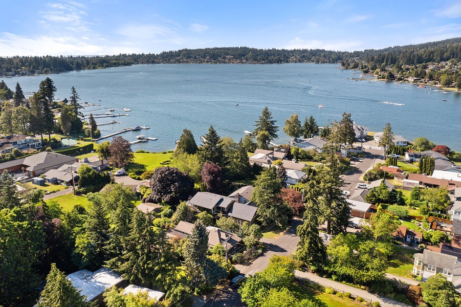 Aerial view of a peaceful lakefront community with tree-lined residential streets, private docks, and stunning natural surroundings.