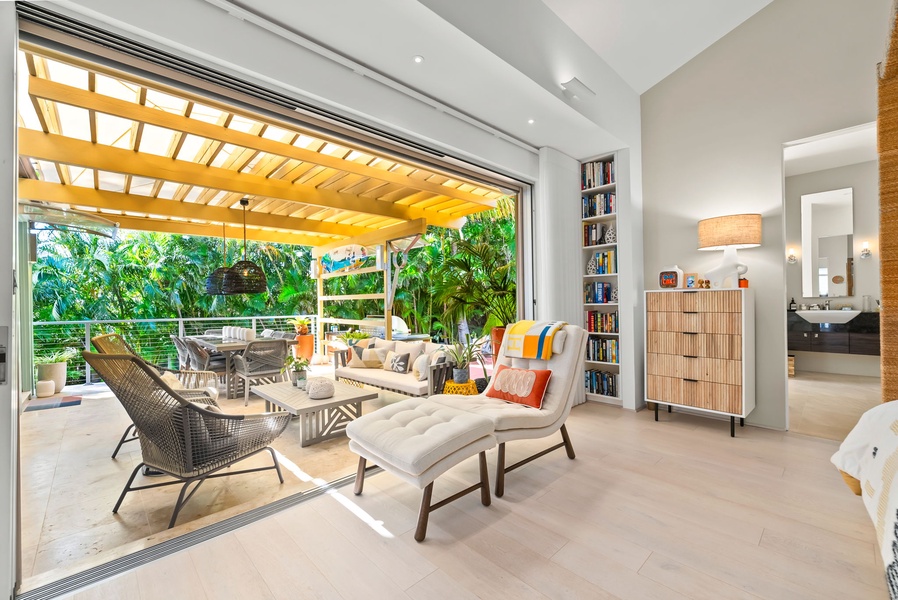 Primary bedroom's floor-to-ceiling sliders opening to a shaded lanai.