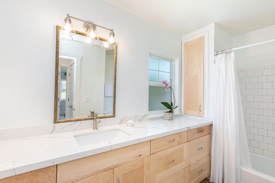 Modern bathroom with double sinks, wood cabinetry, and clean lines throughout.