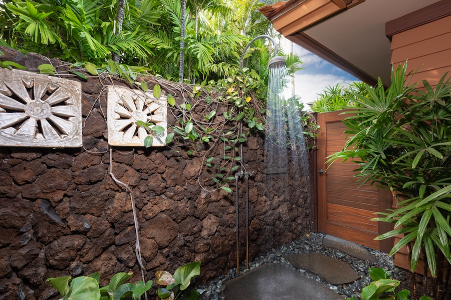 Refreshing outdoor shower surrounded by lush island greenery.