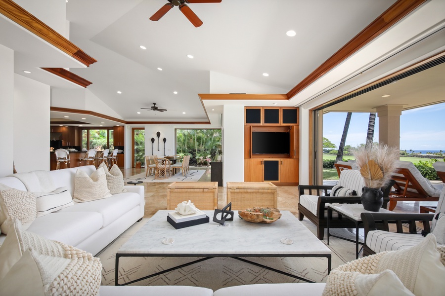 Living room with elegant seating, built in entertainment system, view of the pool deck & ocean beyond.