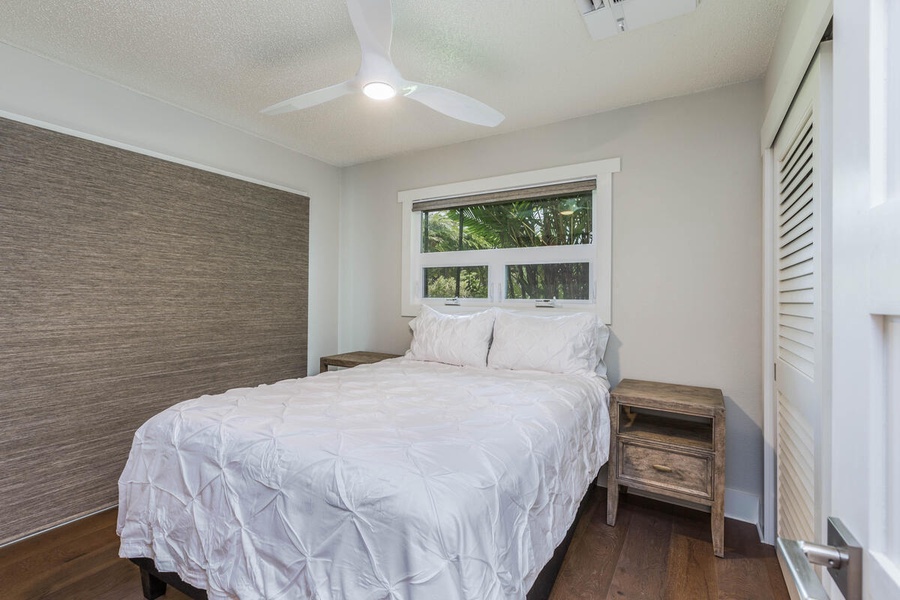 Guest bedroom at Lani Oasis with a cozy queen bed and serene window view for restful nights.