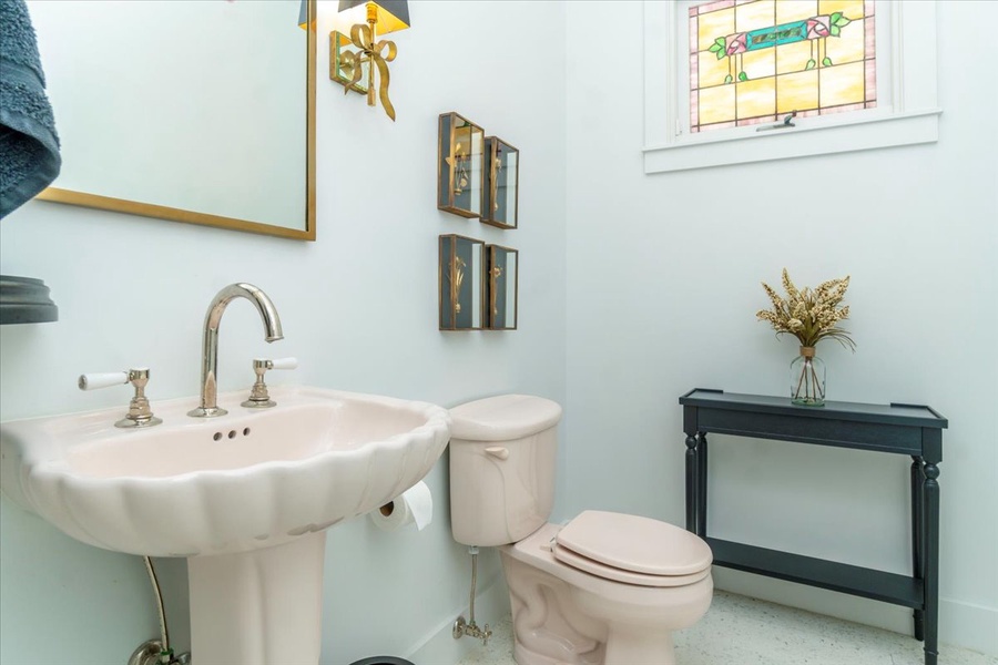 Whimsical half-bath with pedestal sink and stained glass window.