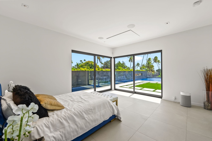 Corner bedroom opening to the pool and lawn through expansive glass.